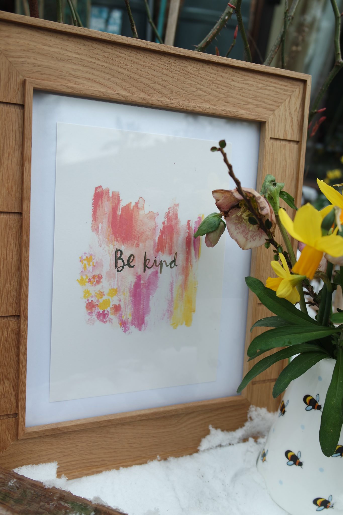 daffodils in a bee covered white jug pink yellow bee kind sign in the snow
